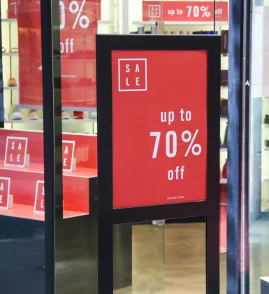 A footwear storefront with multiple red sale signs advertising discounts of up to 70% off.